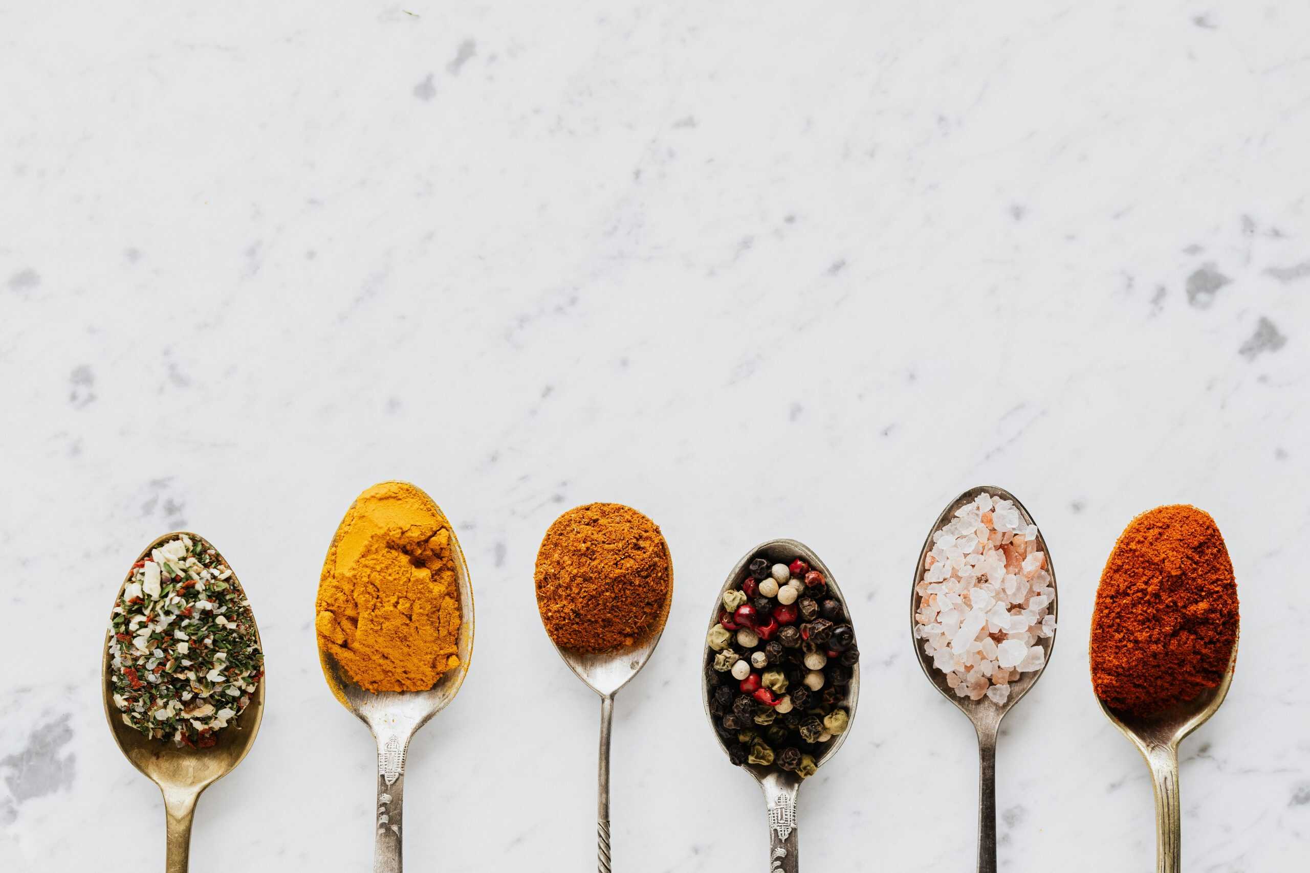 different herbs and spices on spoons